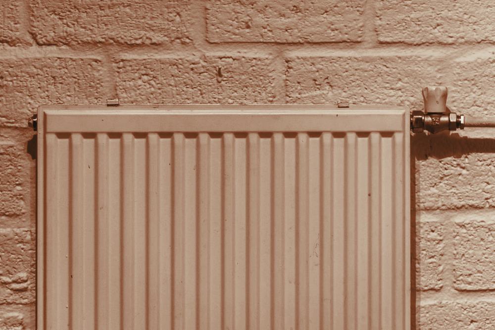 A white radiator mounted on an exposed brick wall in a Bristol terrace