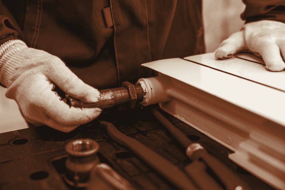 A gloved engineer fitting a valve to a white radiator