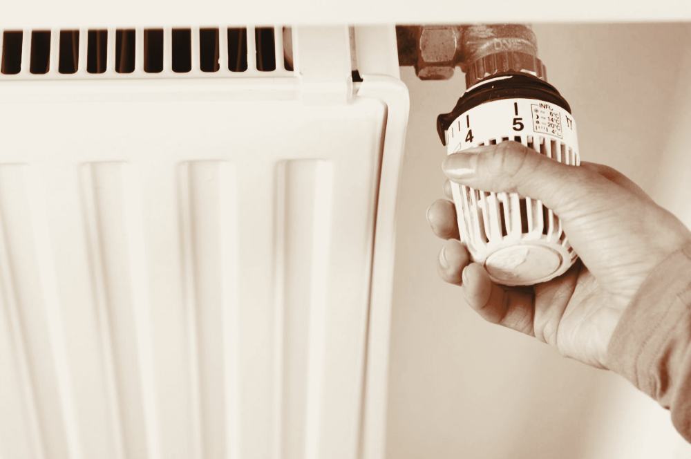 A gloved hand adjusting a radiator valve during an emergency heating repair